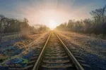 Scenic view of railway going straight ahead to rising sun