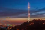 Amazing panoramic view of High Castle hill with illuminated TV tower against picturesque sunset sky, Lviv, Ukraine.