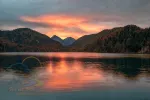 Picturesque sunset over Alpsee Lake with burning sky reflected in the water, Bavaria, Germany
