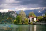Scenic view of Lake Bled with castle, villas and mountains covered by clouds on background at springtime, Slovenia